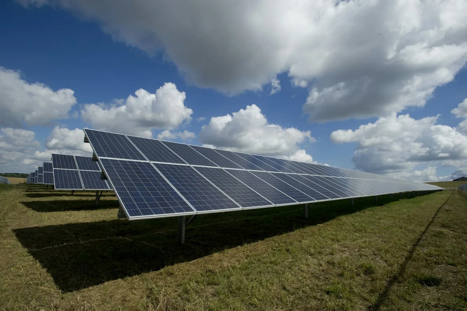 A field of solar panels under a cloudy sky
